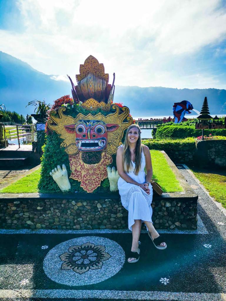 Balijska dekoracja na terenie Pura Ulun Danu Bratan na Bali z kobietą siedzącą obok.