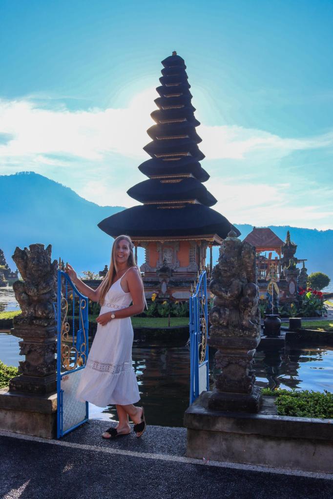 Kobieta przy bramie z widokiem na Pura Ulun Danu Bratan, świątynię na wodzie na Bali.